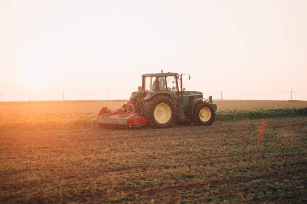 Bilde av traktor på en åker. Kjørende med landbruksdekk.